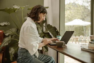 a woman sitting at a table using a laptop computer