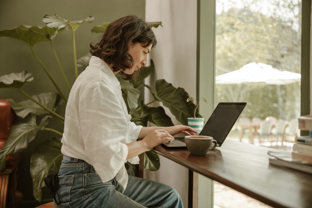 a woman sitting at a table using a laptop computer