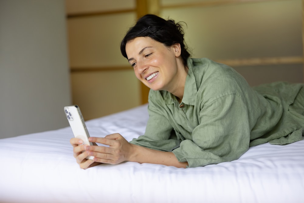 a woman laying on a bed looking at a cell phone