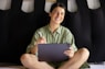 a woman sitting on a bed holding a tablet