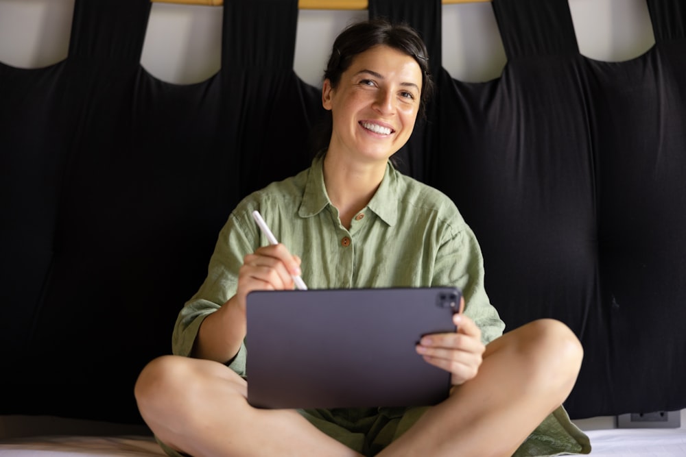 a woman sitting on a bed holding a tablet