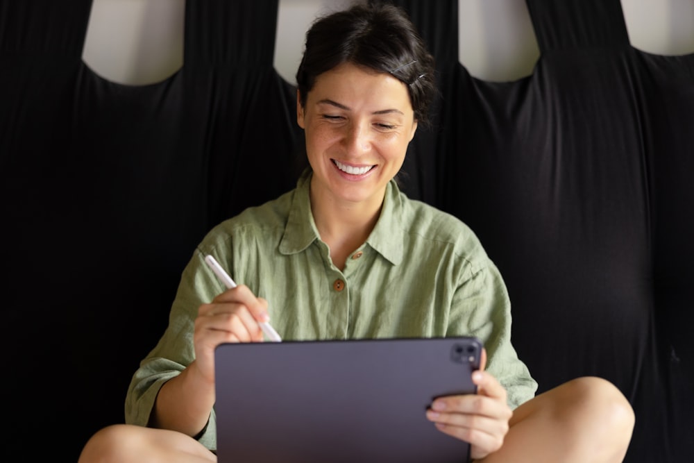 a woman sitting on the floor holding a tablet