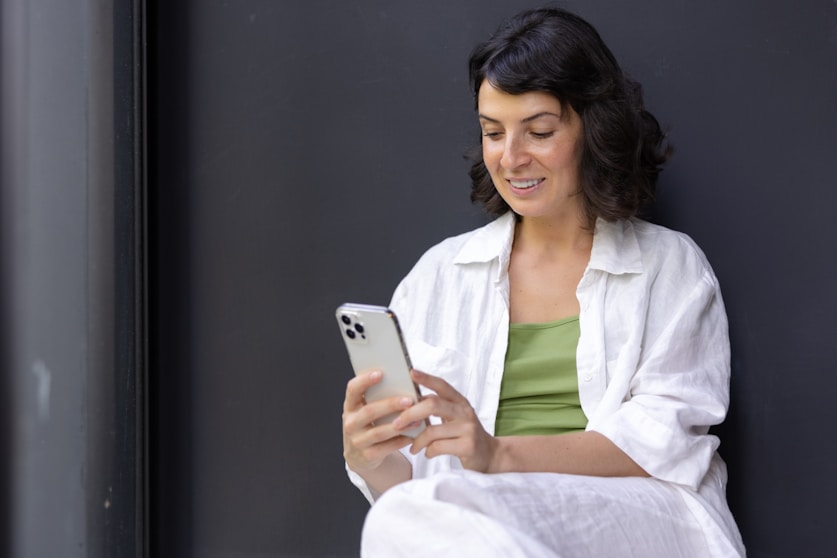a woman sitting on the ground looking at her cell phone