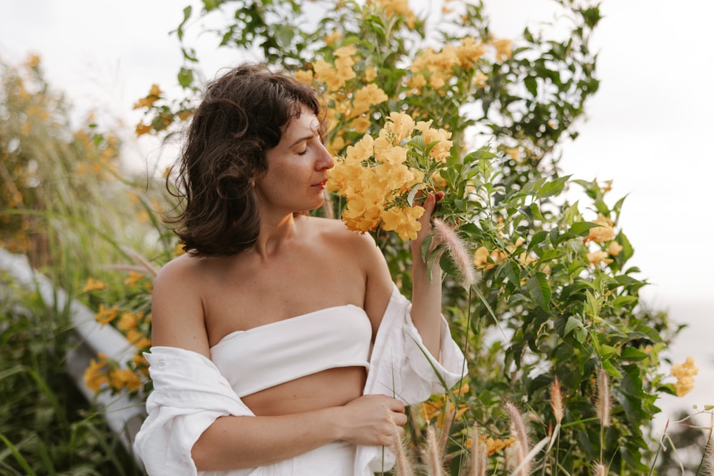 a woman in a white dress holding a yellow flower