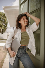 a woman leaning against a door holding a laptop