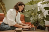 a woman sitting at a table using a laptop computer