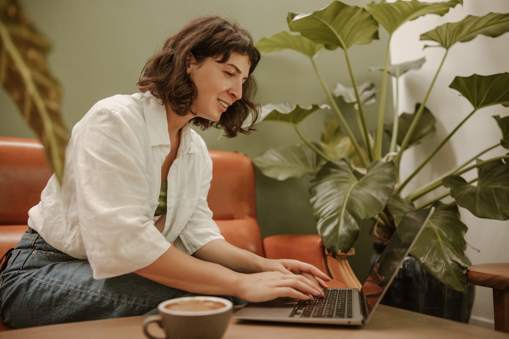 a woman sitting at a table using a laptop computer