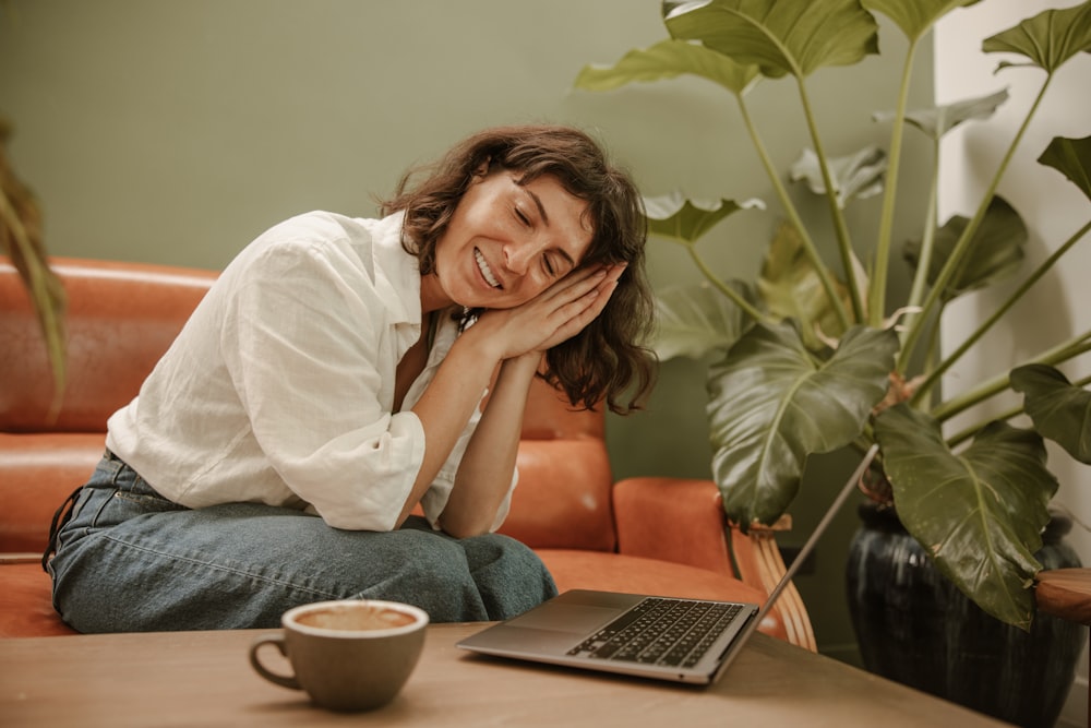 a woman sitting on a couch next to a laptop