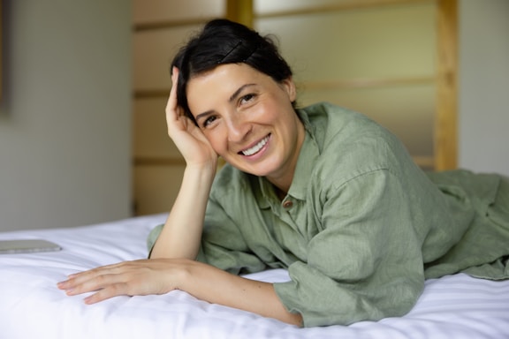 a woman laying on top of a bed next to a laptop computer