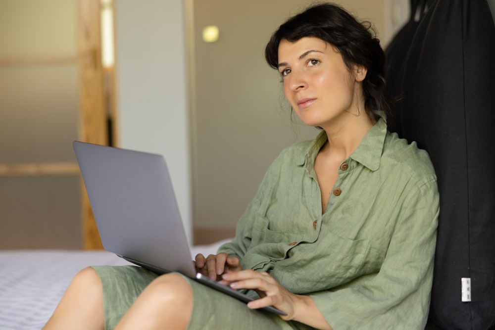 a woman sitting on a bed using a laptop computer