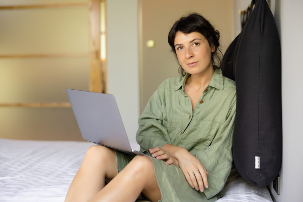 a woman sitting on a bed using a laptop computer