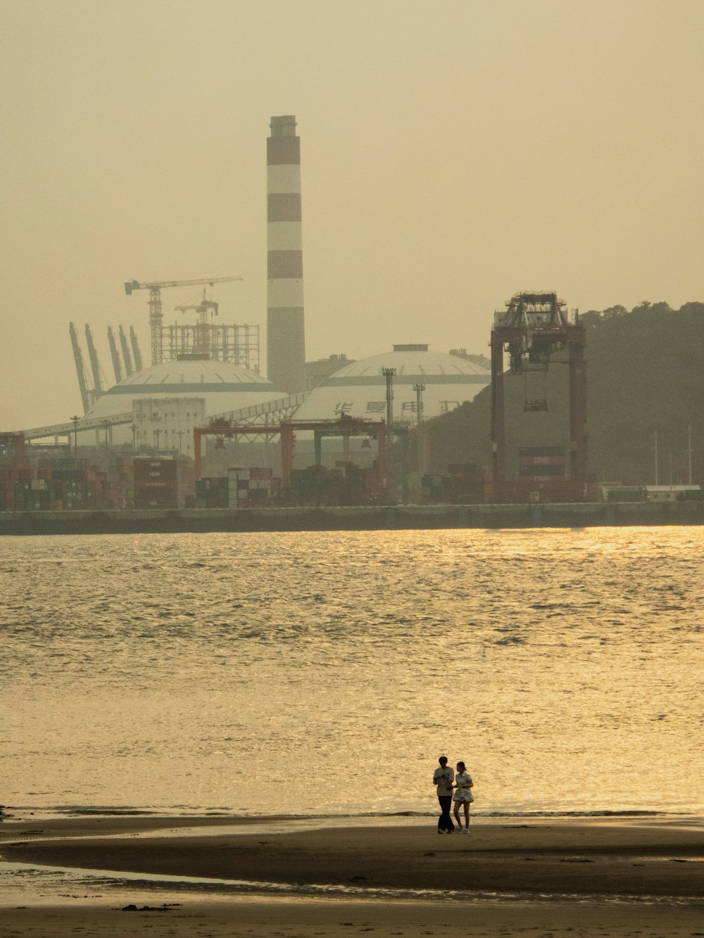 a couple of people standing on top of a sandy beach