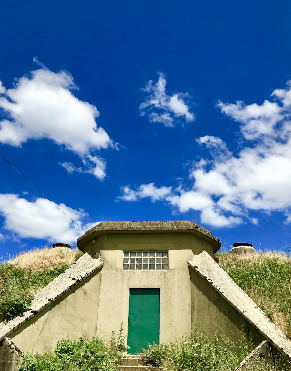 Un bâtiment avec une porte verte sur une colline