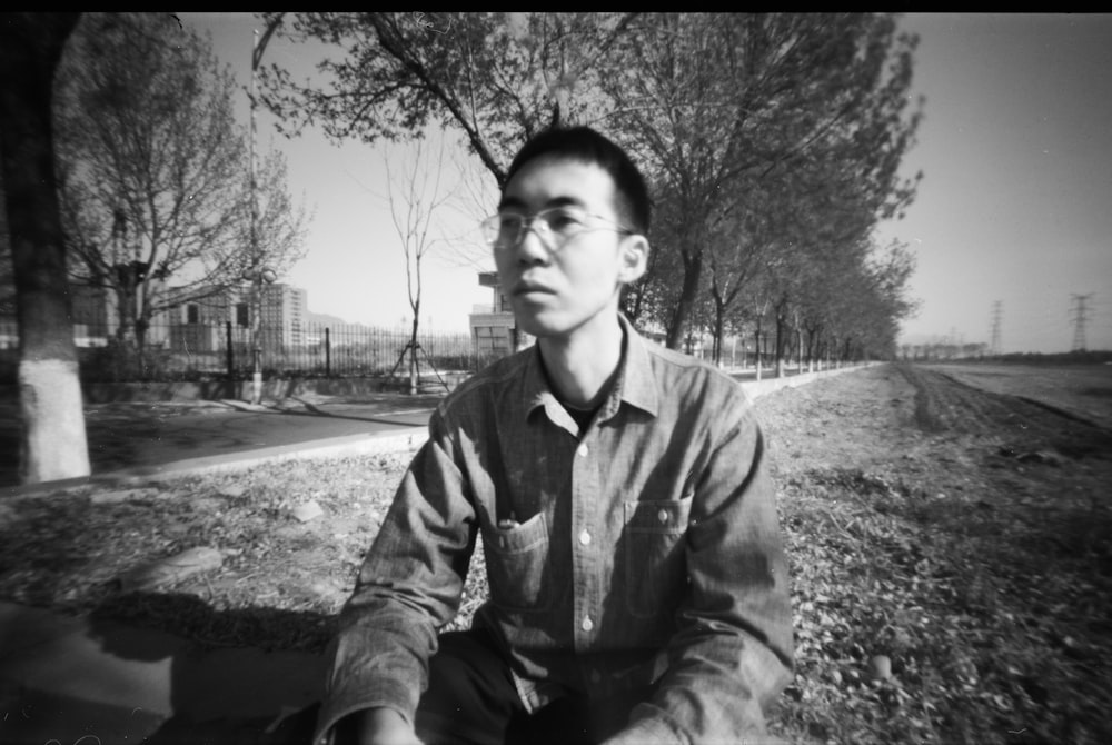 a black and white photo of a man sitting on the ground