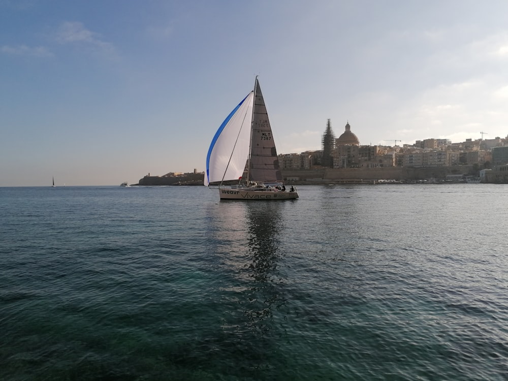 a sailboat sailing in the ocean near a city