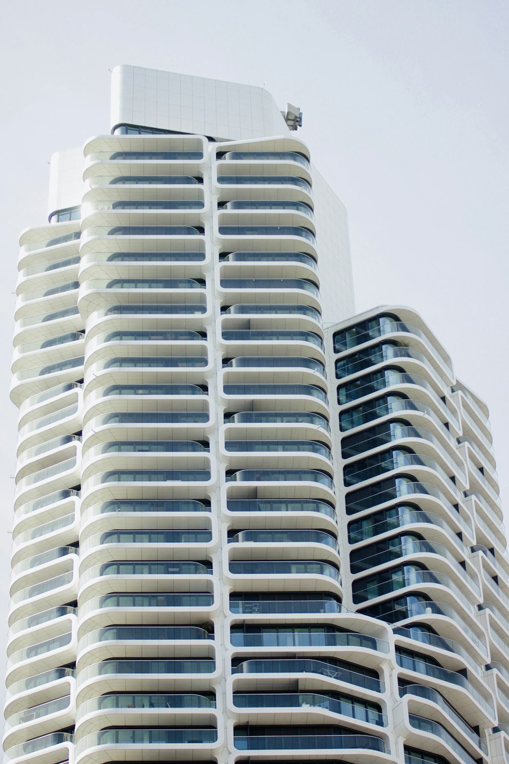 a tall white building with balconies on top of it