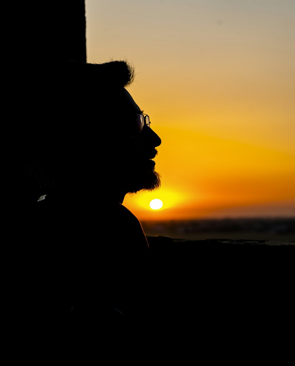 a man with a beard and glasses looking at the sunset