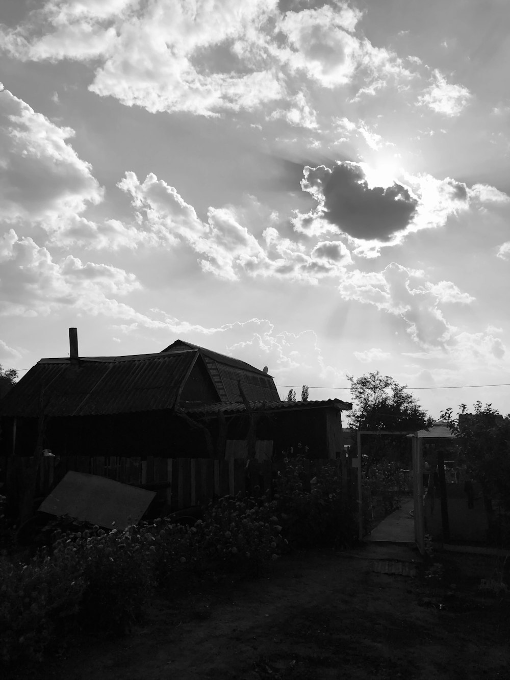 a black and white photo of a house and clouds