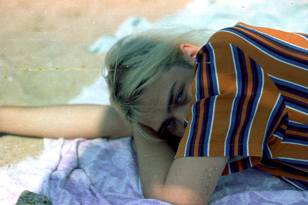 a woman laying on top of a purple blanket