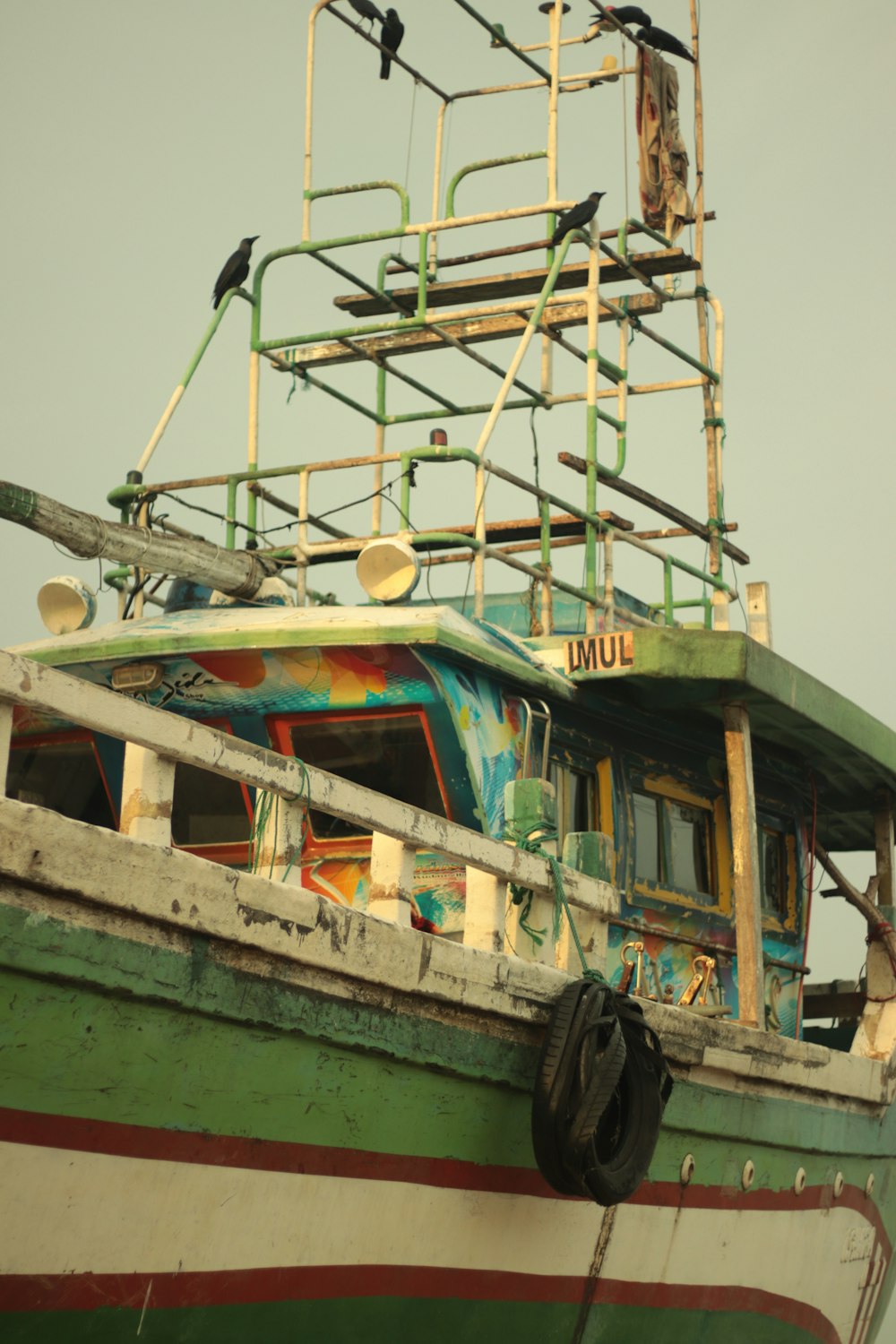 a green and white boat sitting on top of a beach