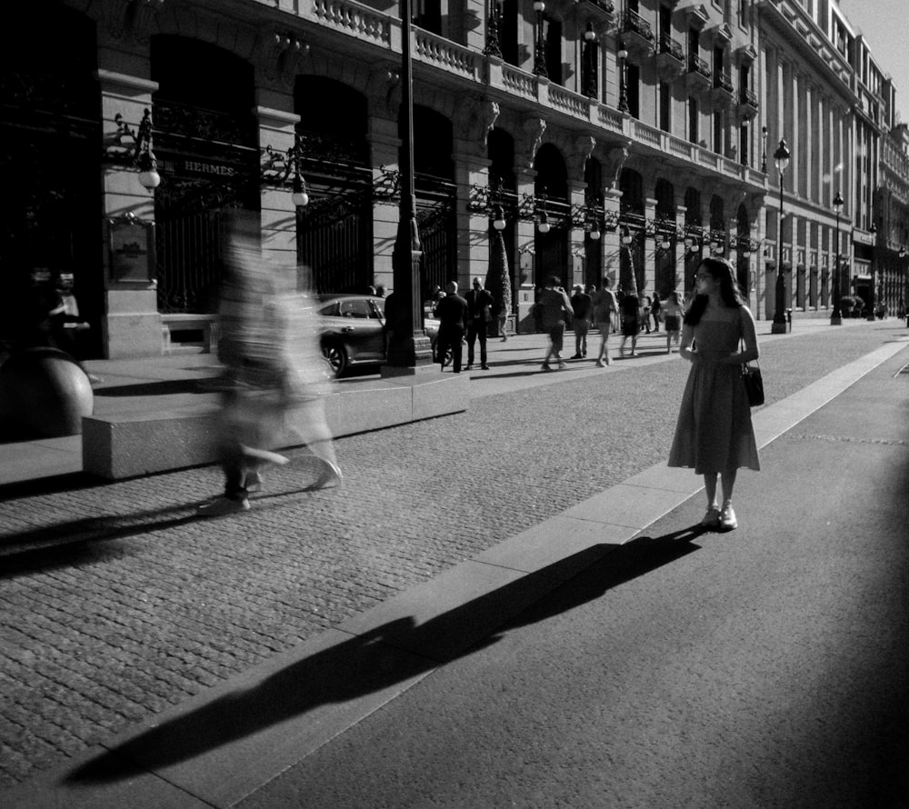 a woman walking down a street next to tall buildings