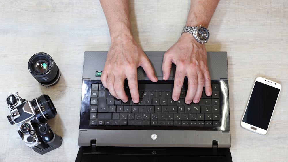 a person typing on a laptop with their hands on the keyboard