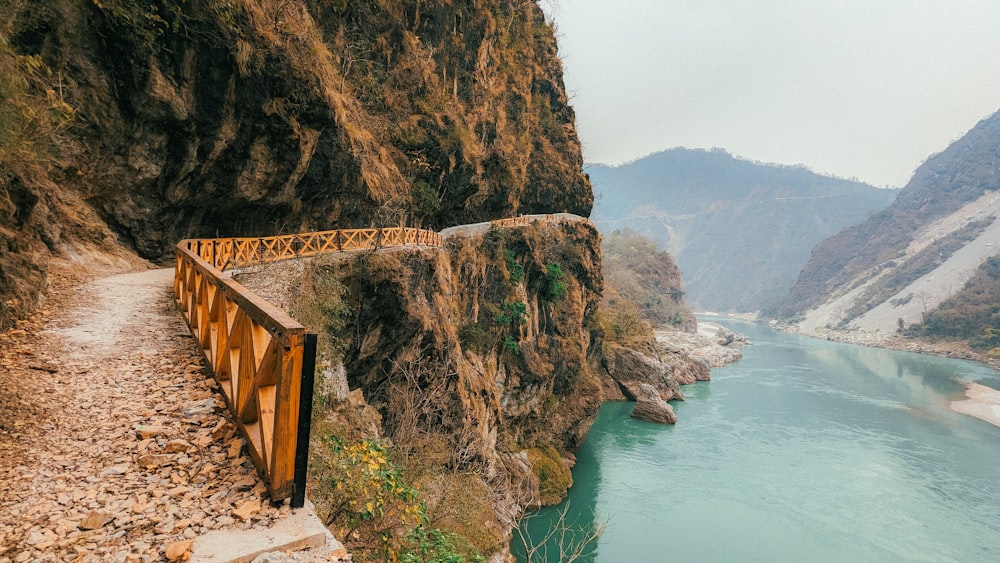 a wooden bridge over a river next to a mountain