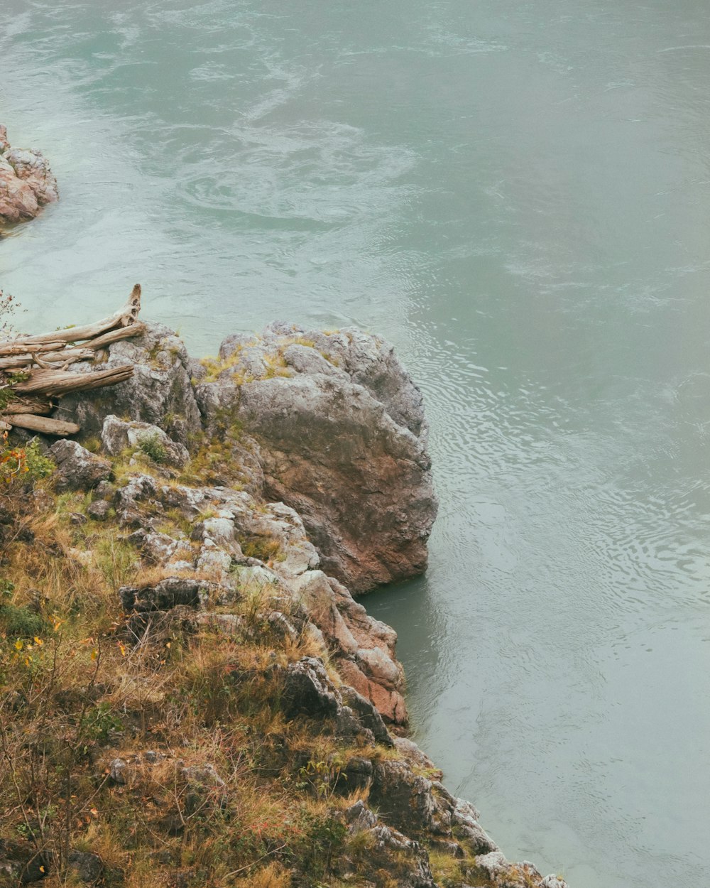 a couple of sheep standing on top of a cliff next to a river