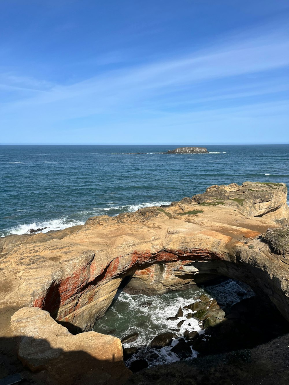 una persona sentada en la cima de una gran roca cerca del océano
