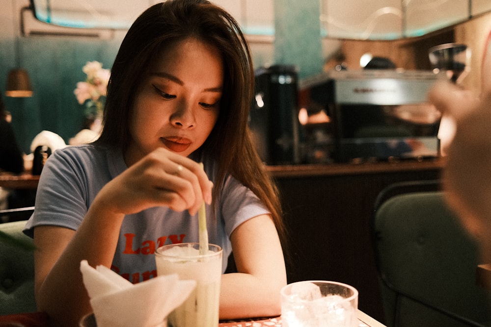 a woman sitting at a table with a drink