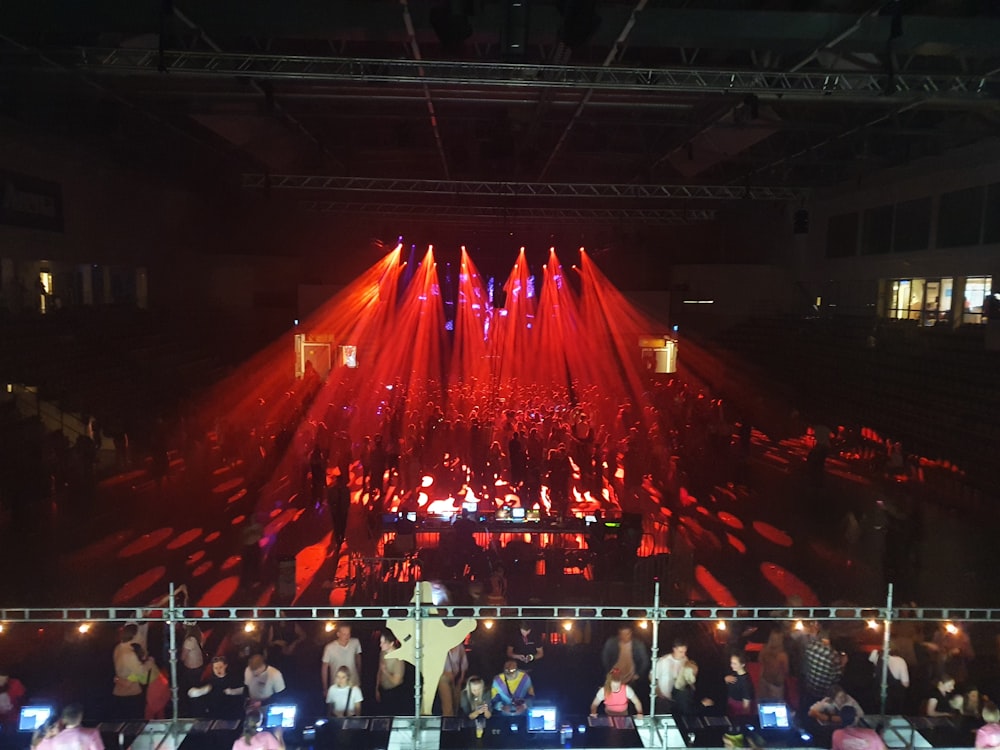 a crowd of people standing around a stage with red lights