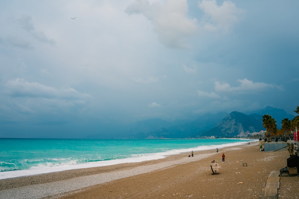 a sandy beach with a few people walking on it