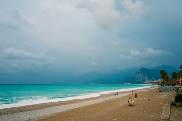 A sandy beach with a few people walking on it — Patara, Turkey