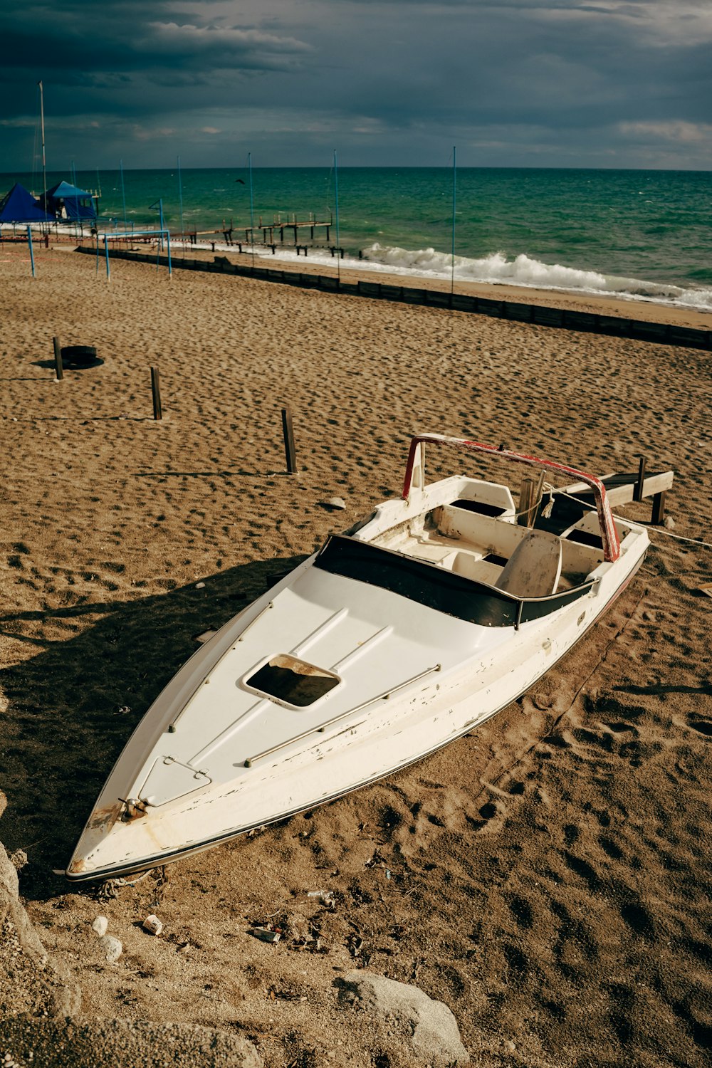 a white boat sitting on top of a sandy beach