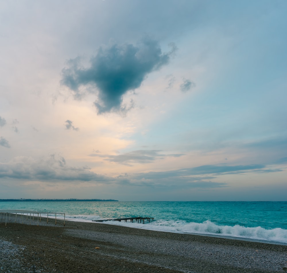 a cloudy sky over the ocean with a pier in the foreground