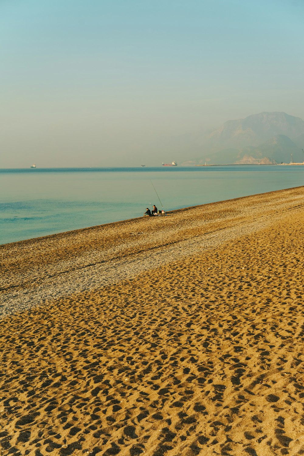 a sandy beach with a body of water in the background