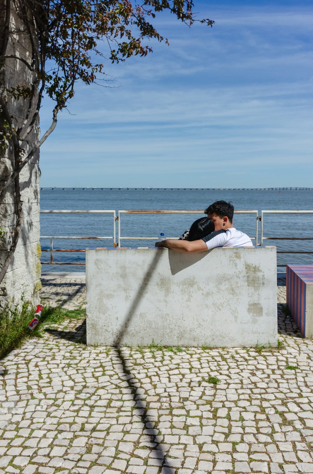 a man sitting on a cement wall next to a body of water