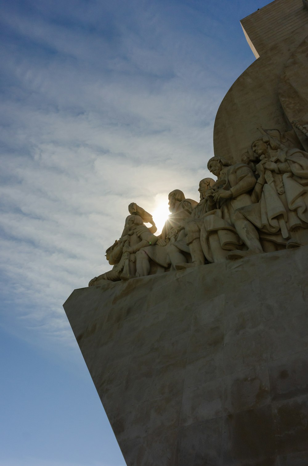 a statue of a group of people with a sun in the background