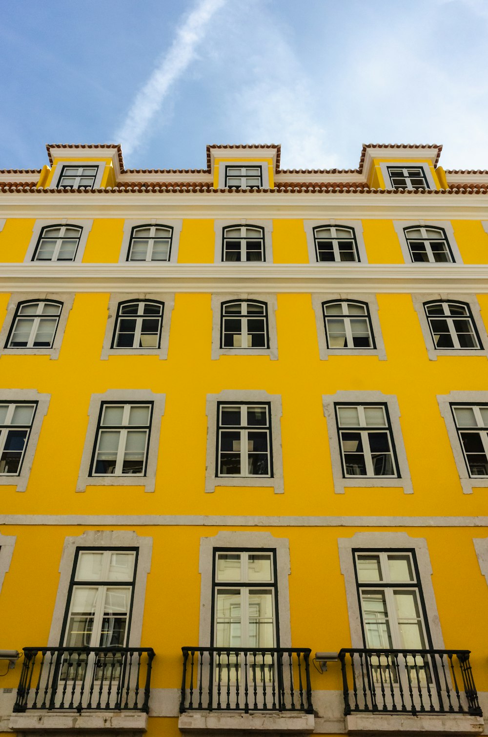 a tall yellow building with many windows and balconies