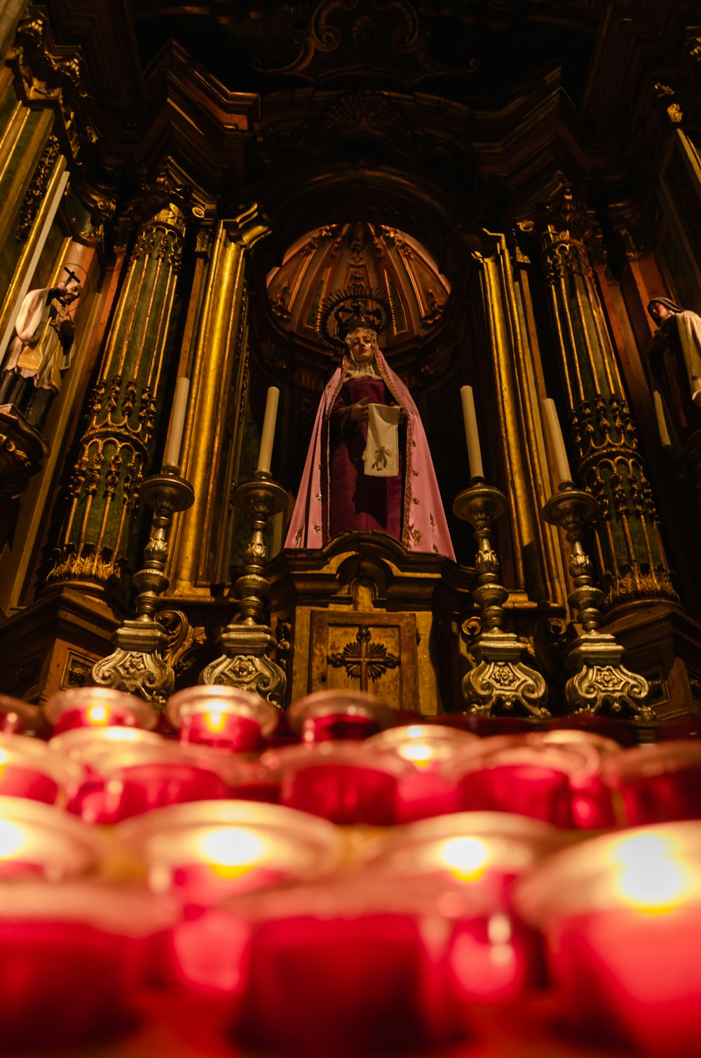 a statue of a person in a church surrounded by candles