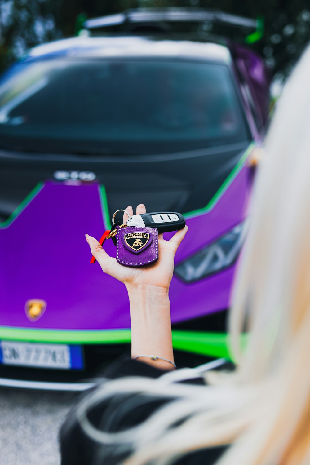 a woman holding a cell phone in front of a purple sports car
