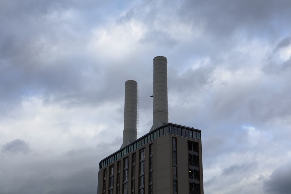 two smoke stacks rise from a building under a cloudy sky
