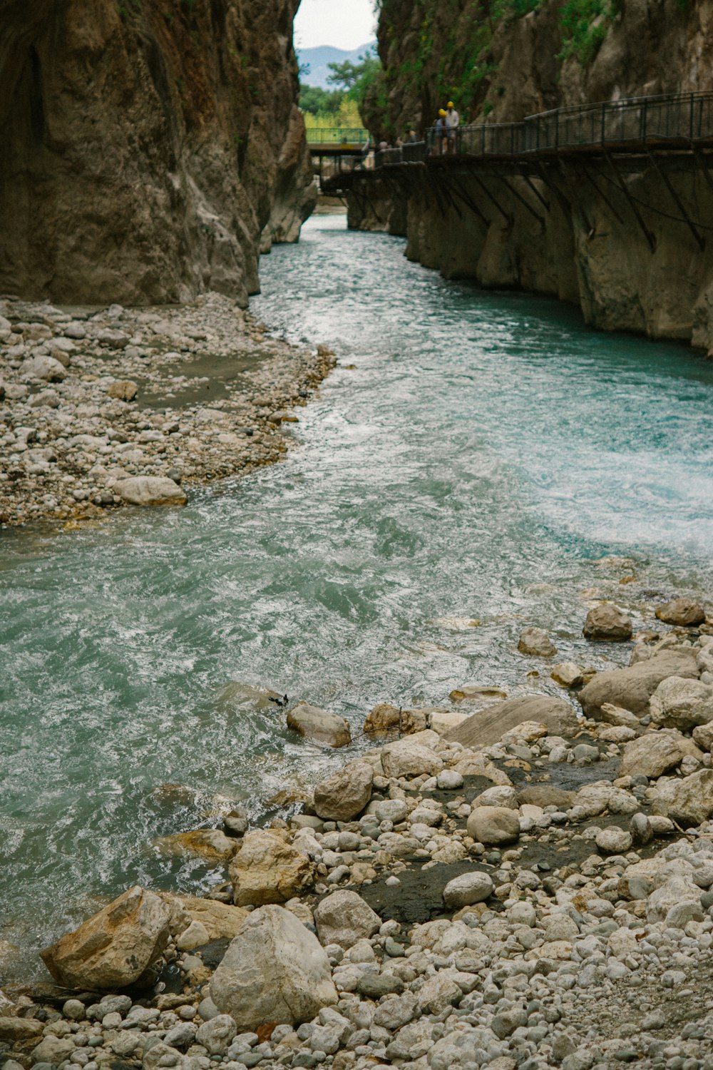 a river running through a canyon next to a bridge