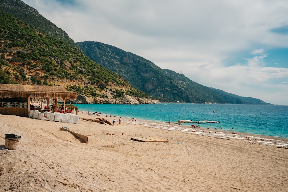 a sandy beach with people on it and a mountain in the background