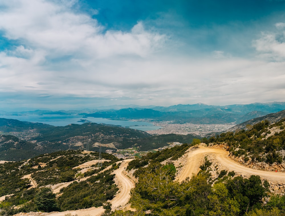 a dirt road going up a hill with mountains in the background