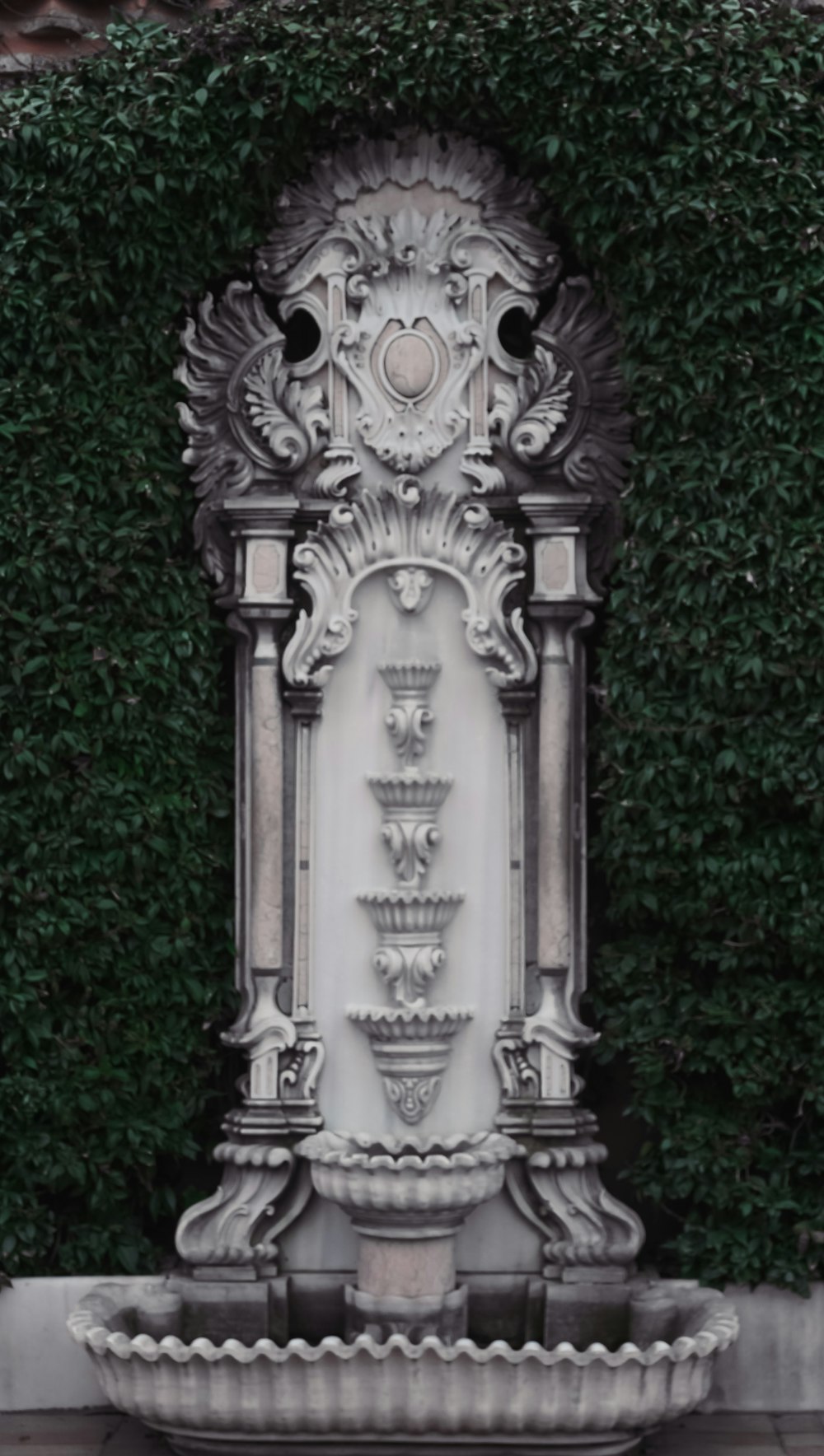 a water fountain in front of a green wall