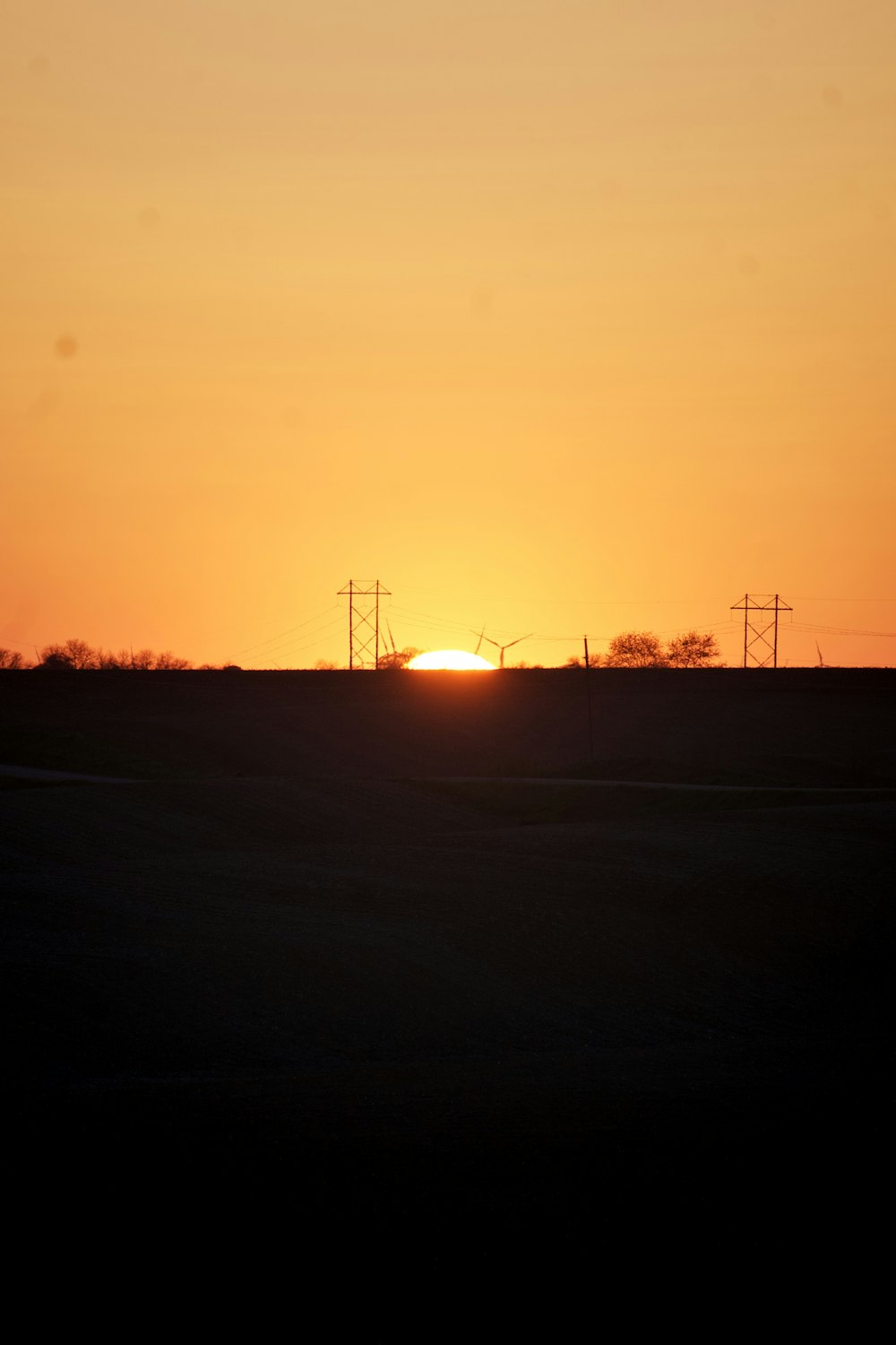 the sun is setting over the horizon of a field