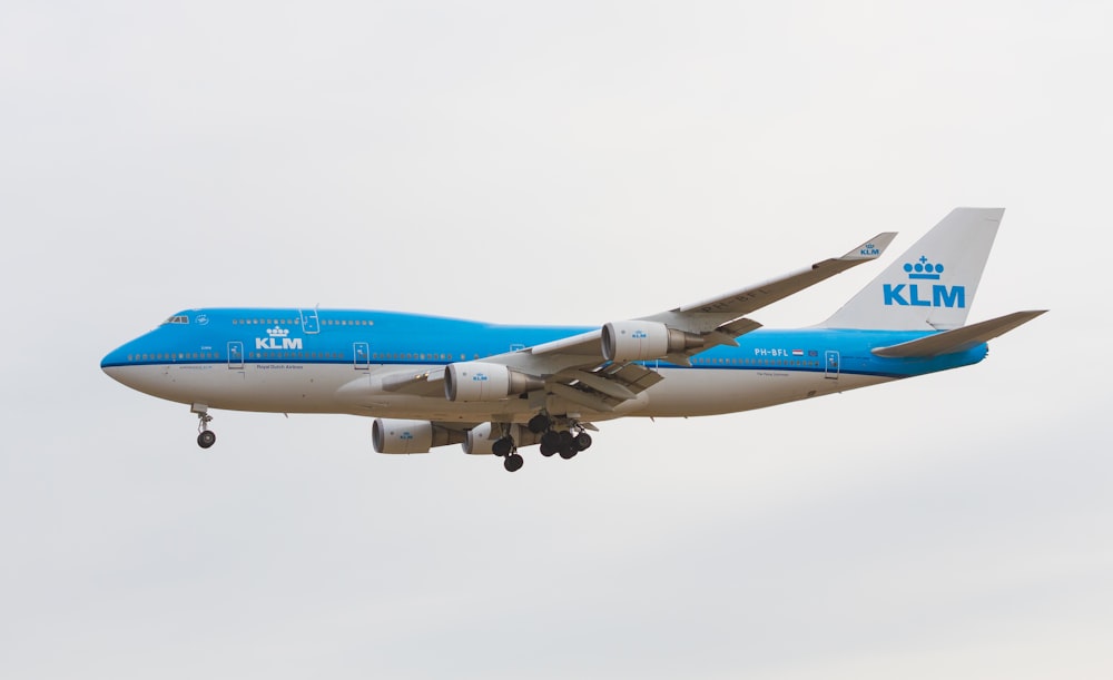 a blue and white klm airplane flying in the sky