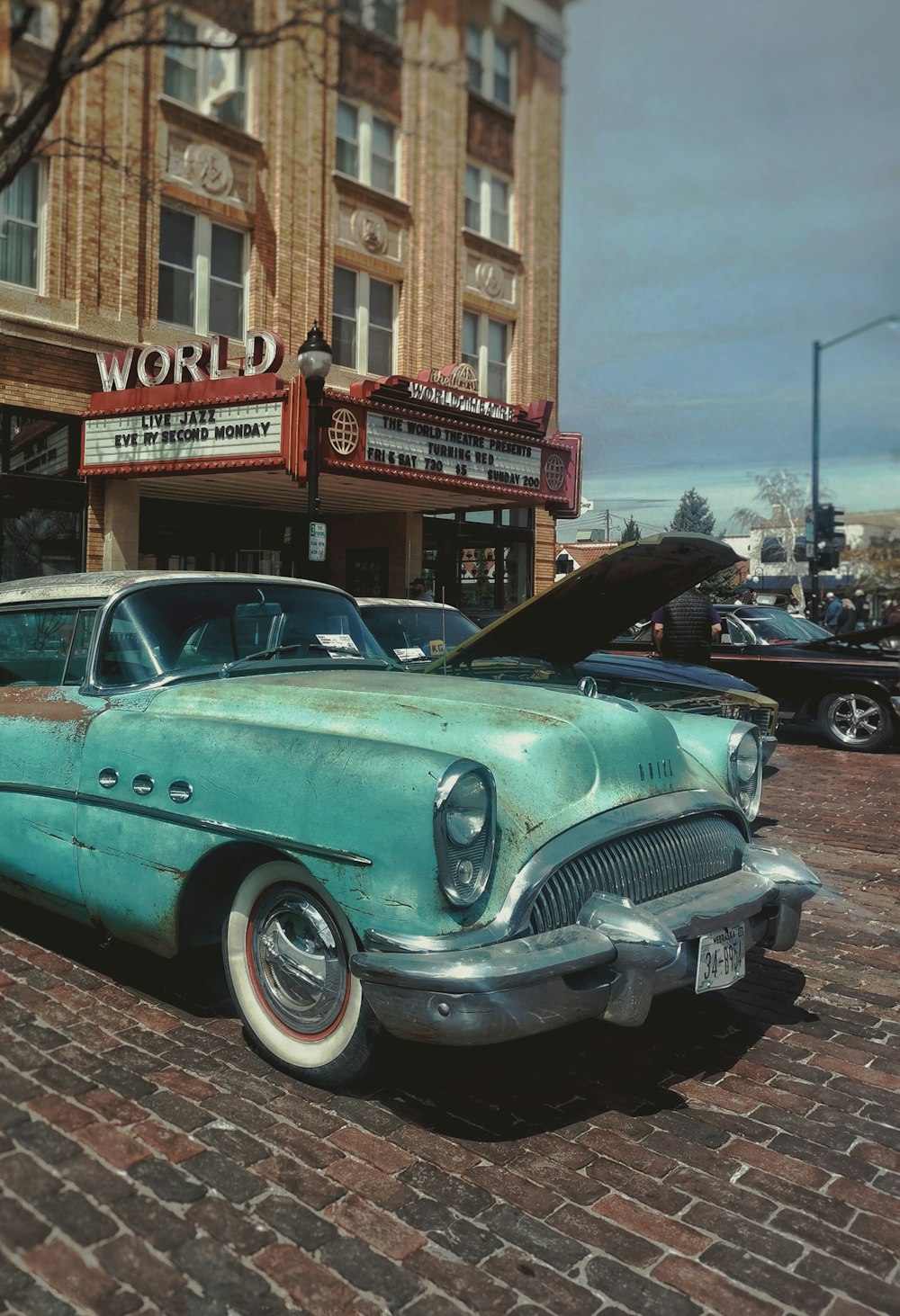 an old car parked in front of a movie theater