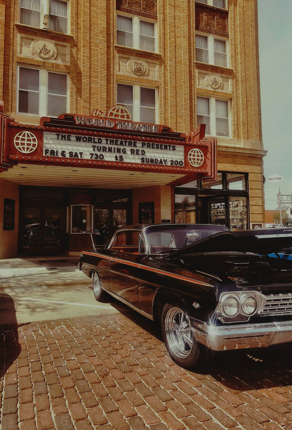 a black car parked in front of a theater